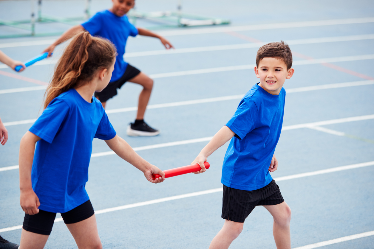 Children In Athletics Team Competing In Relay Race On Sports Day